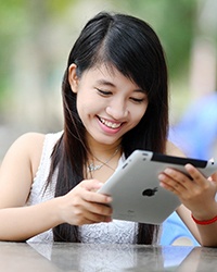 Young woman is sitting outdoors looking at a tablet